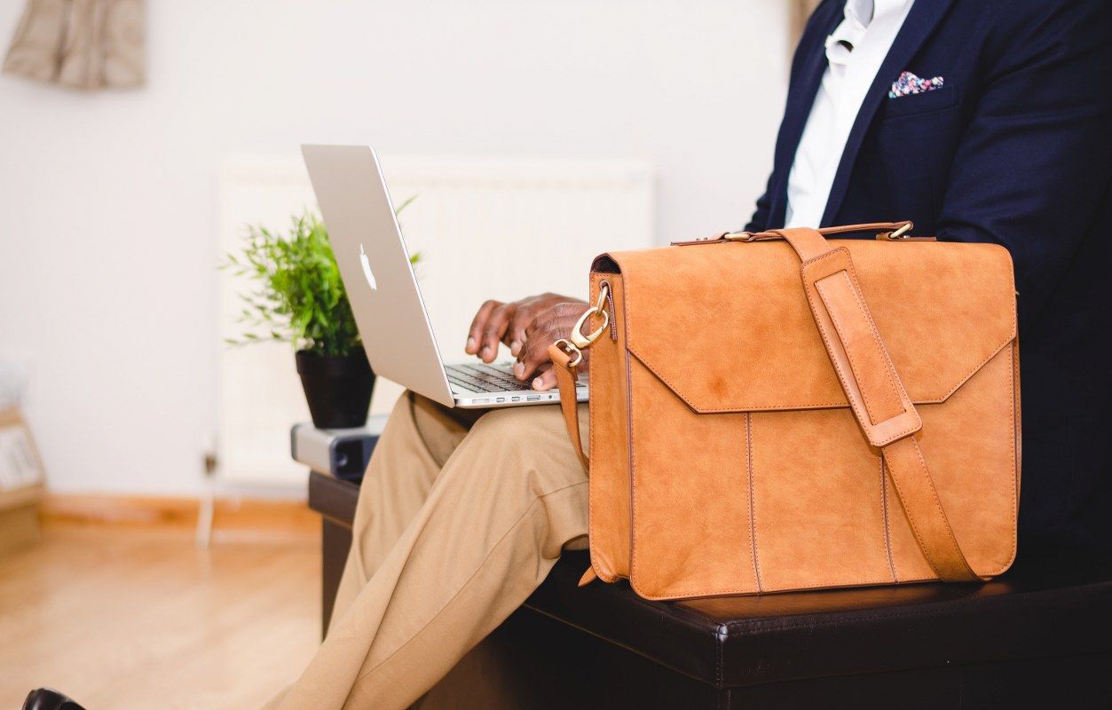 A man in a suit with a brow suitcase behind his laptop starting with e-invoicing